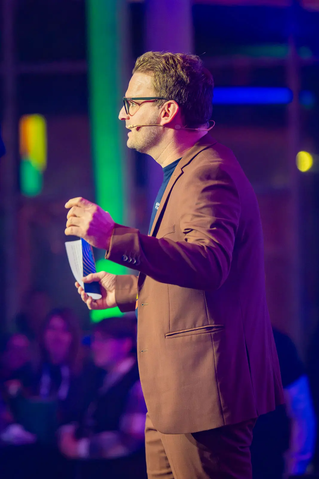 Lukas Schult moderiert mit Headset vor Publikum